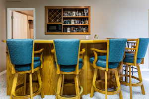 Bar with black microwave and carpet flooring