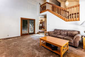 Carpeted living room with a towering ceiling