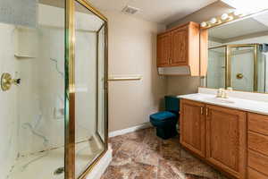 Bathroom with vanity, toilet, an enclosed shower, and a textured ceiling