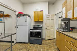 Kitchen featuring white refrigerator and stainless steel electric range oven