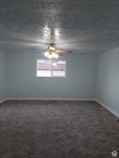 Carpeted empty room featuring ceiling fan and a textured ceiling