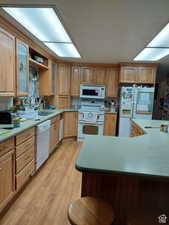 Kitchen with light brown cabinetry, sink, white appliances, and light hardwood / wood-style flooring