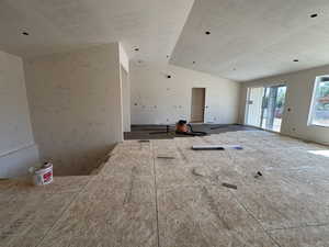 Unfurnished living room featuring vaulted ceiling and a textured ceiling