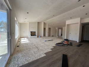 Unfurnished living room with plenty of natural light, vaulted ceiling, wood finished floors, and a textured ceiling