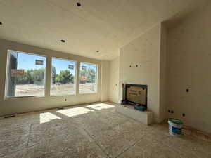 Unfurnished living room featuring a textured ceiling and vaulted ceiling