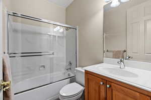 Second ensuite full bathroom with vanity, shower/bath combination with glass door, and toilet