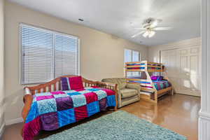 Fourth bedroom with ceiling fan, concrete flooring, a closet