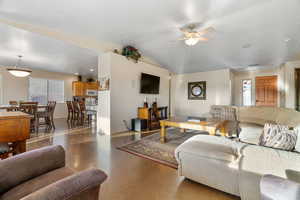 Living room with lofted ceiling, concrete flooring, and ceiling fan