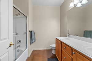 Third bull bathroom with toilet, vanity, and bath/shower combo with glass door