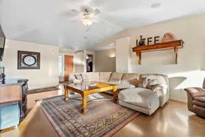 Living room featuring lofted ceiling, concrete floors, and ceiling fan