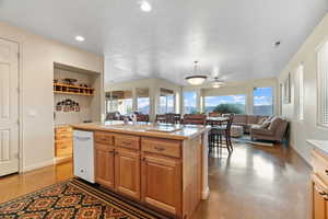 Kitchen featuring dishwasher, a kitchen island with sink, plenty of natural light, and concrete floors