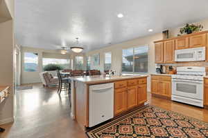 Kitchen featuring white appliances, tasteful backsplash, an island with sink,  and decorative light fixtures