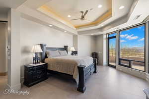 Bedroom with a raised ceiling, access to outside, and ceiling fan