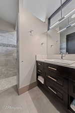 Bathroom featuring tiled shower and vanity