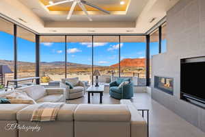 Living room with a tile fireplace, a raised ceiling, floor to ceiling windows, a mountain, city, and golf course view