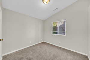 Carpeted empty room with vaulted ceiling