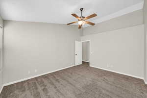 Unfurnished room featuring ceiling fan, lofted ceiling, and carpet flooring