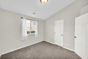 Carpeted spare room featuring lofted ceiling