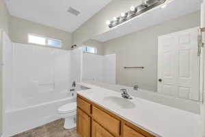 Full bathroom featuring shower / tub combination, vanity, toilet, and tile patterned flooring