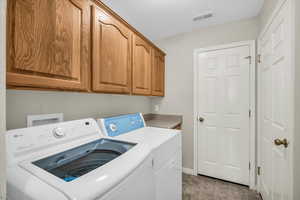 Laundry area featuring cabinets, washing machine and dryer, and a textured ceiling