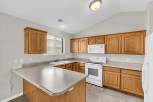 Kitchen featuring vaulted ceiling, sink, white appliances, and kitchen peninsula