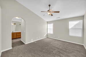 Carpeted empty room with lofted ceiling and ceiling fan