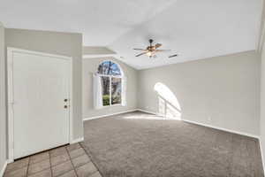 Empty room with ceiling fan, light colored carpet, and lofted ceiling