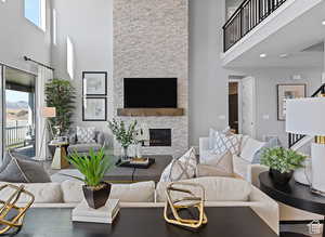 Living room featuring a fireplace, a healthy amount of sunlight, and a high ceiling