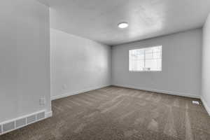 Carpeted spare room featuring a textured ceiling