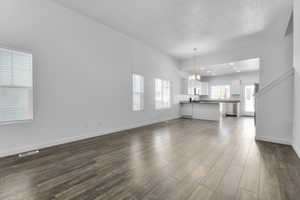 Unfurnished living room with an inviting chandelier and dark hardwood / wood-style flooring