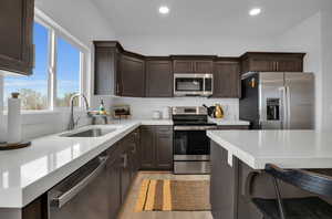 Kitchen featuring sink, light hardwood / wood-style flooring, stainless steel appliances, and a kitchen bar