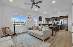 Living room with ceiling fan, sink, and light wood-type flooring