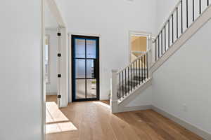 Foyer entrance with a towering ceiling and light hardwood / wood-style floors