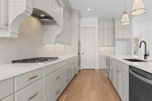 Kitchen featuring sink, dishwasher, hanging light fixtures, stainless steel gas cooktop, and light wood-type flooring