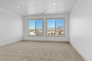 Empty room with light colored carpet, a mountain view, and a wealth of natural light