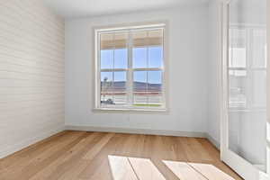 Unfurnished room featuring a mountain view, wooden walls, and light wood-type flooring