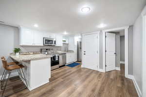 Kitchen with white cabinetry, appliances with stainless steel finishes, sink, and a breakfast bar area