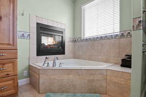 Bathroom with tile patterned flooring, a tile fireplace, and a relaxing tiled tub