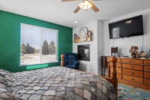 Bedroom featuring hardwood / wood-style flooring, ceiling fan, and a fireplace