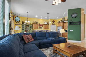 Living room featuring ceiling fan with notable chandelier and light hardwood / wood-style flooring