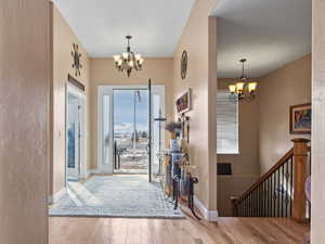 Entryway with plenty of natural light, an inviting chandelier, and light hardwood / wood-style floors