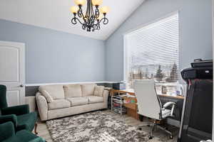 Home office with a notable chandelier, vaulted ceiling, and light wood-type flooring