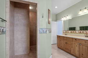 Bathroom featuring vanity, tile patterned flooring, and a tile shower