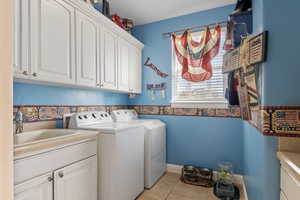 Washroom featuring cabinets, sink, light tile patterned floors, and independent washer and dryer