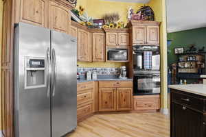 Kitchen with light hardwood / wood-style flooring and black appliances