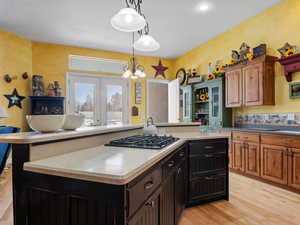 Kitchen with stainless steel gas cooktop, a center island, a chandelier, and light hardwood / wood-style floors