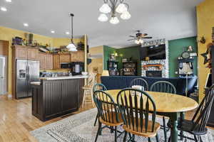 Dining space featuring a stone fireplace, ceiling fan, and light wood-type flooring