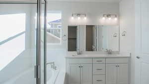 Full bath featuring a bath, double vanity, and a sink