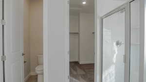 Full bath featuring a walk in closet, baseboards, toilet, and a shower stall