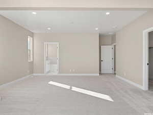 Unfurnished bedroom featuring connected bathroom, a walk in closet, and light colored carpet